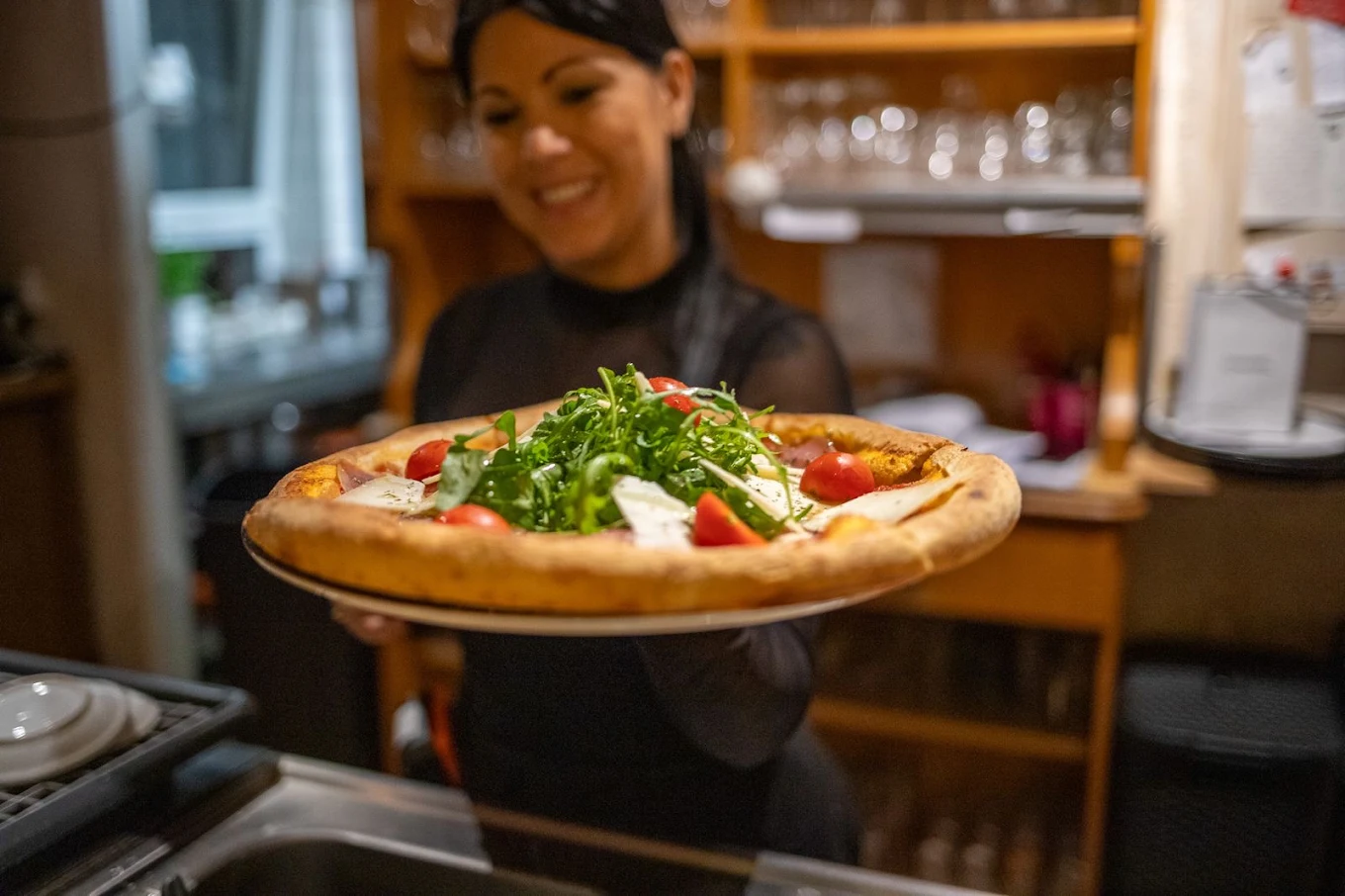 Frisch servierte Pizza mit Rucola und Tomaten im Antichi Sapori